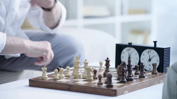 περικομμένη θέα του ανώτερου ανθρώπου παίζοντας σκάκι και πατώντας το κουμπί στο σκάκι ρολόι - Πλάνα, βίντεο