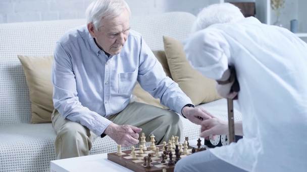 dois homens seniores jogando xadrez e pressionando botão no relógio de xadrez na sala de estar
 - Filmagem, Vídeo