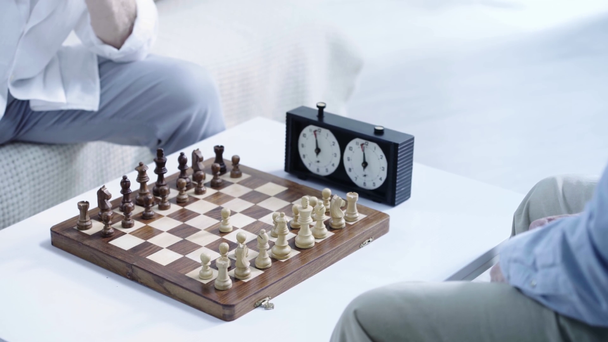 vista ritagliata di due uomini anziani che giocano a scacchi e premendo il pulsante sull'orologio a scacchi
 - Filmati, video