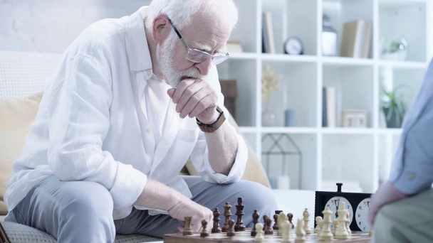 pokovatý vousatý muž v brýlích hraných šachy s protivníkem a tlačením tlačítka na šachových hodinách - Záběry, video