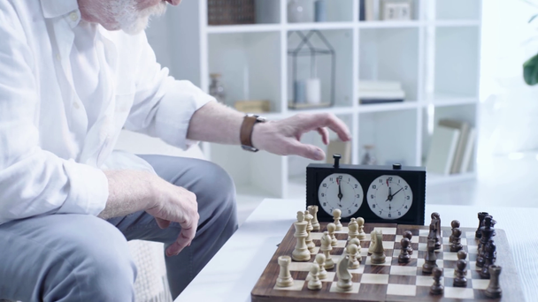 przycięte widok starszy mężczyzna w zegarek na rękę i naciskając przycisk na Zegar szachowy - Materiał filmowy, wideo