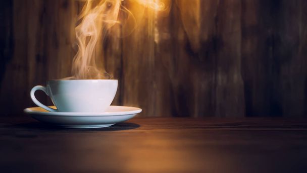 white cup with coffee and steam on wooden table - Foto, Bild