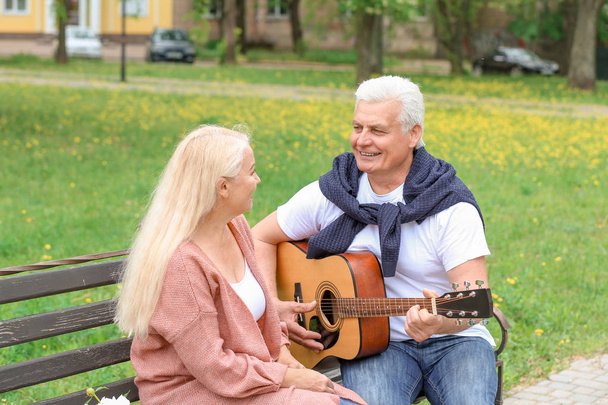 Homme mûr jouant de la guitare pour sa femme dans le parc
 - Photo, image