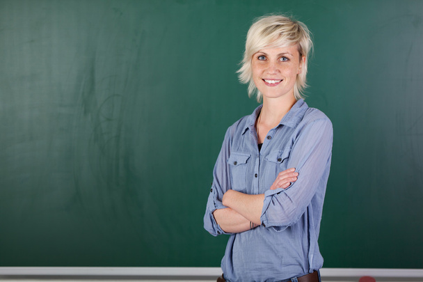 Confident Young Female Teacher In Front Of Chalkboard - Foto, Bild
