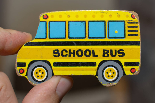 Крупним планом зношений іграшковий жовтий шкільний автобус-головоломка з дорослою рукою. Концептуальні
. - Фото, зображення
