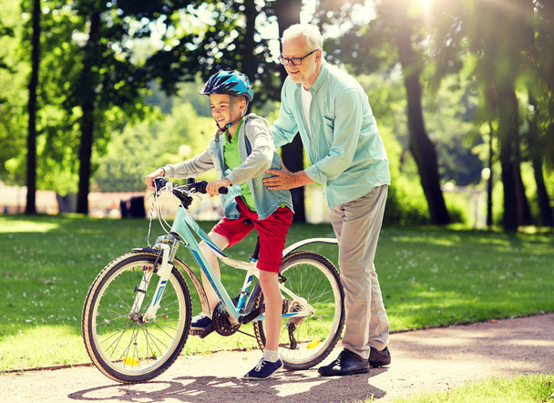 grandfather and boy with bicycle at summer park - Foto, afbeelding