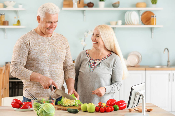 Portrait of happy mature couple cooking in kitchen - Photo, Image