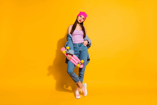 Full length body size photo pretty beautiful she her lady amazing nice look hand arm skate board adore fond of dangerous sport wear casual jeans denim jacket shoes pink hat isolated yellow background - Fotoğraf, Görsel