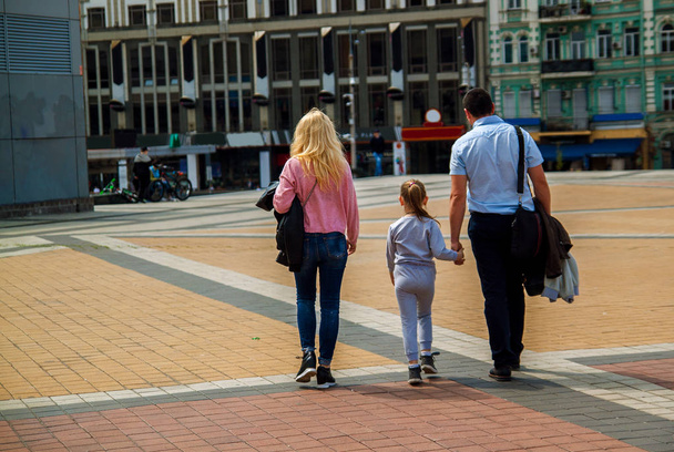 Rückansicht einer glücklichen Familie, die Händchen haltend durch die Straßen der Altstadt geht.  - Foto, Bild
