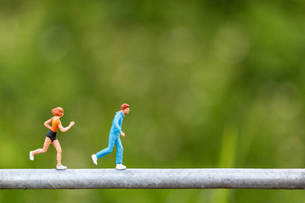 Miniatuur mensen: jonge mensen die op een draad lopen  - Foto, afbeelding