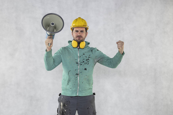 le travailleur de la construction tient un mégaphone dans ses mains, le conc
 - Photo, image