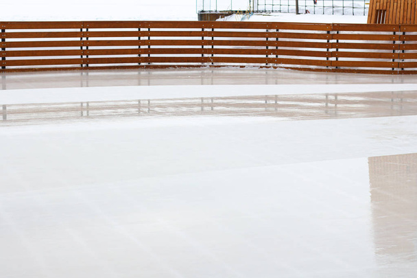 Zimní prázdné kluziště pro bruslení a hokej s dřevěným zábradlím, s mostem na pozadí - Fotografie, Obrázek
