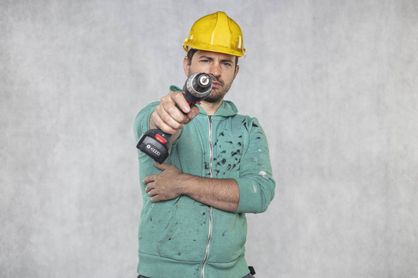 the construction worker holds an electric screwdriver in his han - Photo, Image