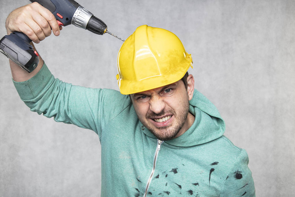 the construction worker holds an electric screwdriver in his han - Фото, зображення