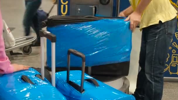 Gepäckverpackungsservice am Flughafen, der Koffer ist in Zellophan-Frischhaltefolie verpackt. Arbeiter wickelten Gepäck in Plastik - Filmmaterial, Video