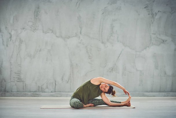 Spor giyim çekici uyum Kafkas esmer mat yalınayak üzerinde Poz Dizin yoga Revolved Kafa yapıyor. - Fotoğraf, Görsel
