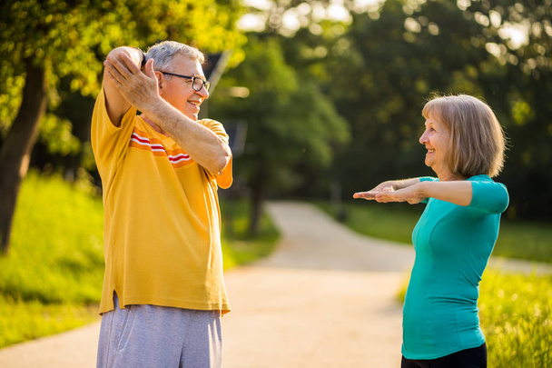 Senior couple is exercising in park. - Foto, afbeelding