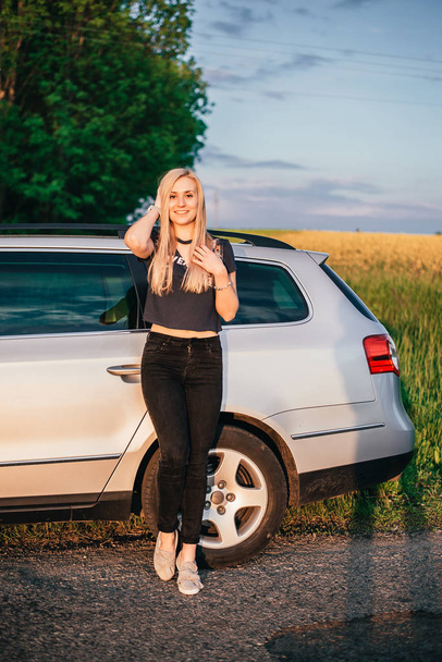 portrait of beautiful young woman standing near car on nature - Photo, Image