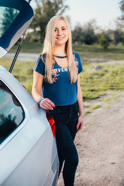 portrait of beautiful young woman standing near car on nature - Fotoğraf, Görsel