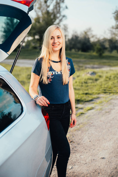 portrait of beautiful young woman standing near car on nature - Fotó, kép