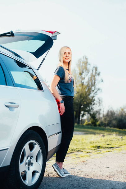 portrait of beautiful young woman standing near car on nature - Foto, Imagem