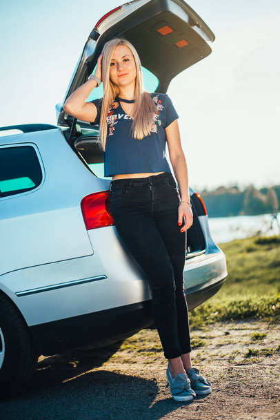 portrait of beautiful young woman standing near car on nature - Foto, imagen
