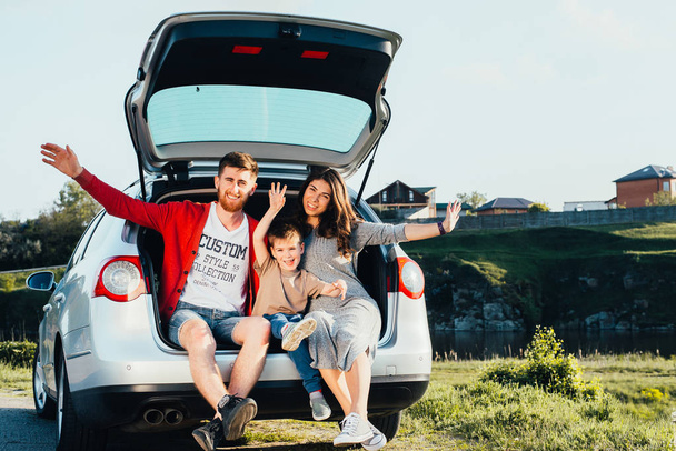 beautiful young family sitting in car trunk on nature - Photo, image