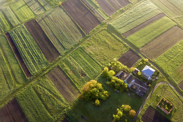 Felülnézet a vidéki táj napos tavaszi napon. Farm ház, ház és pajta a zöld és fekete mezőben másolni tér hátterét. Drone fotózás. - Fotó, kép
