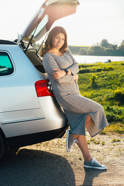 portrait of beautiful young woman standing near car on nature - Foto, afbeelding