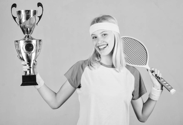 Win tennis game. Woman wear sport outfit. Tennis player win championship. First place. Sport achievement. Celebrate victory. Tennis champion. Athletic girl hold tennis racket and golden goblet - Zdjęcie, obraz