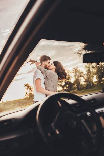 beautiful young couple kissing near car during trip - Photo, Image