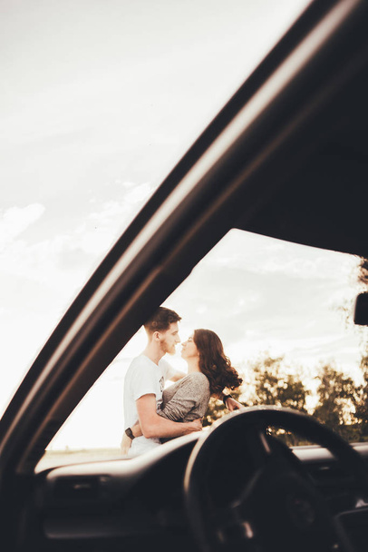 beautiful young couple kissing near car during trip - Foto, Imagem