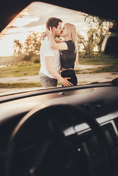 beautiful young couple kissing near car during trip - Foto, afbeelding
