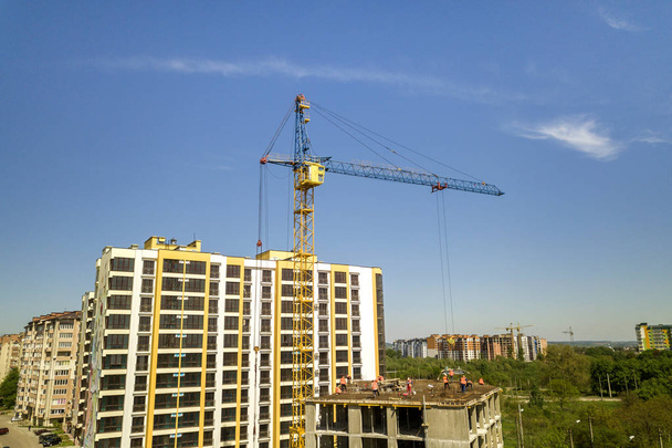 Lakás vagy iroda magas épület építés alatt. Munka építők és torony daruk fényes kék ég másolja tér háttér. - Fotó, kép