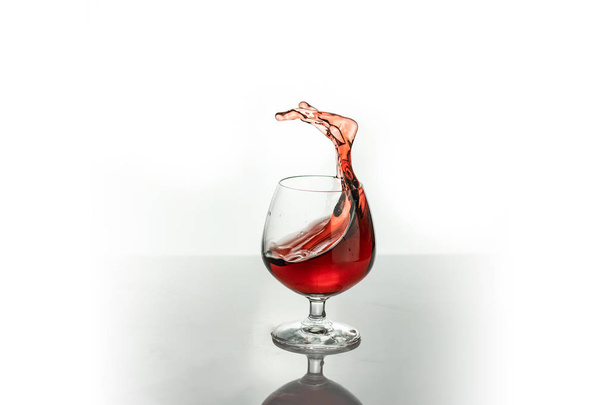 Red wine splashing out of a glass, isolated on white. Concept: alcoholic drinks - Fotografie, Obrázek