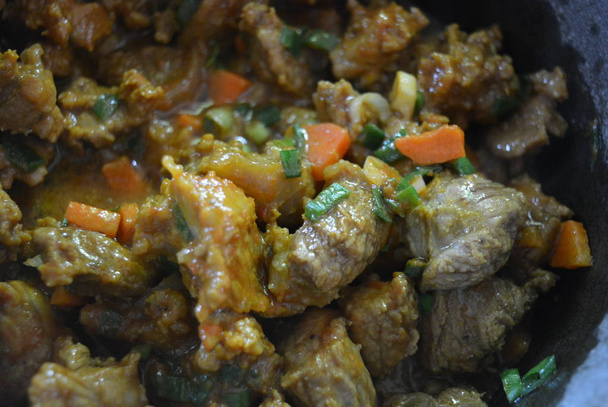 Koken, smakelijk gestoofd vlees van een koe met curry, uien en gesneden wortelen. Heerlijk eten, gezond eten, leven en schoonheid. - Foto, afbeelding
