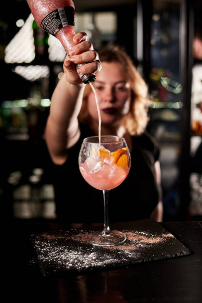 young blonde bartender woman making pink cocktail at bar - Foto, afbeelding
