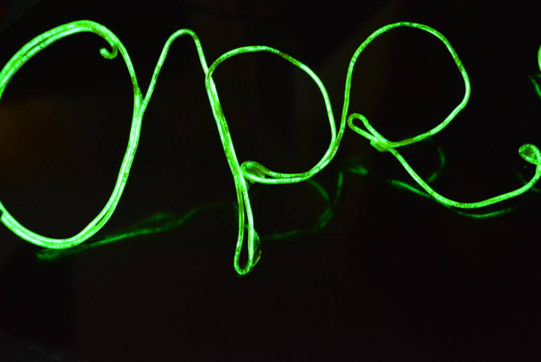 Zelené světlo s určitým vzorem. Tkané vlákna, kabely, dráty s výstupním světlem. Neonový elektrický drát s nápisem a otevřenými písmeny. - Fotografie, Obrázek