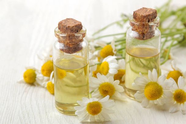 Chamomile. Medicinal little flowers of chamomile with aroma oils on a white wooden table. close-up - Foto, immagini