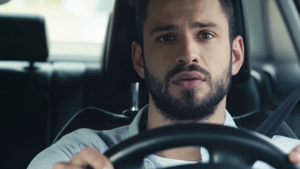 selektywne skupienie przystojnego Brodatego mężczyzny trzymania kierownicy w samochodzie  - Materiał filmowy, wideo