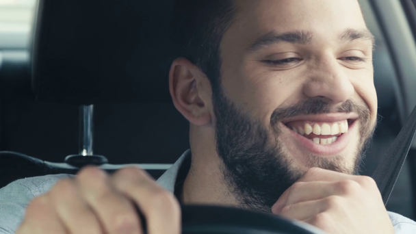 selektywne skupienie szczęśliwego Brodatego mężczyzny trzymania kierownicy podczas jazdy samochodem  - Materiał filmowy, wideo