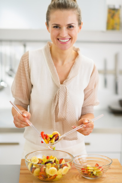 Happy young housewife making fruits salad - Фото, изображение