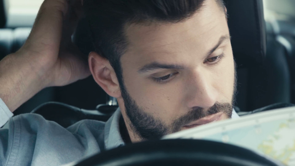 foco seletivo de homem bonito tomando mapa, abrindo e olhando enquanto sentado no carro
  - Filmagem, Vídeo