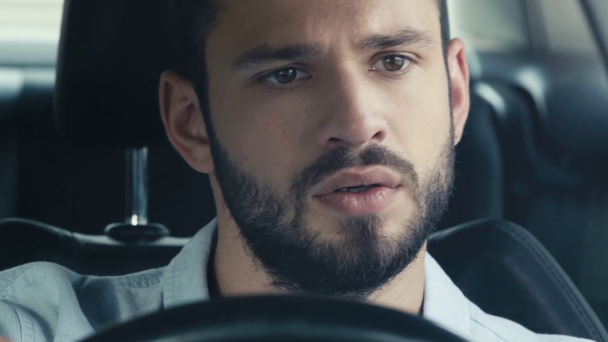 selective focus of sweaty bearded man holding steering wheel and driving car  - Footage, Video