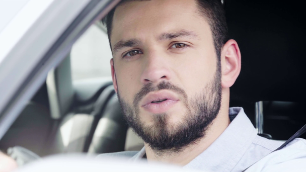 selektivní zaměření okna otevření poblíž vousatého muže s úsměvem při sezení v autě a při pohledu na kameru  - Záběry, video