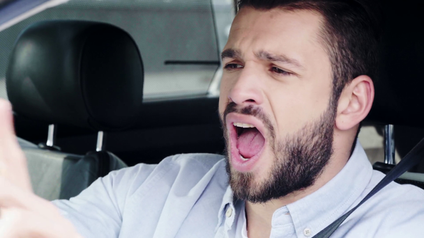 primer plano de hombre guapo haciendo gestos y cantando mientras está sentado en el coche
  - Imágenes, Vídeo