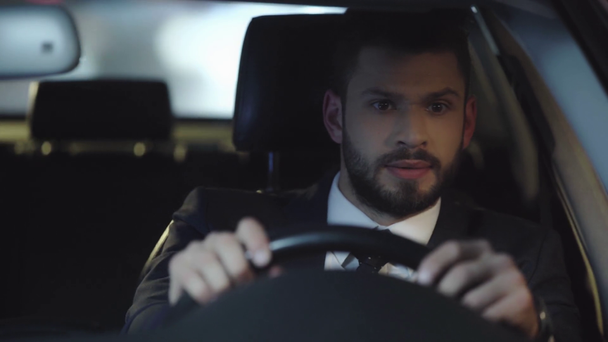 επιλεκτική εστίαση του όμορφου μουσάτο άντρα σε στολή οδήγησης αυτοκίνητο, κορνάρω και τη χειρονομία στο αυτοκίνητο  - Πλάνα, βίντεο