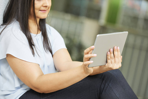 Mujer sentada al aire libre y viendo el nuevo episodio del programa en la computadora tableta
 - Foto, imagen