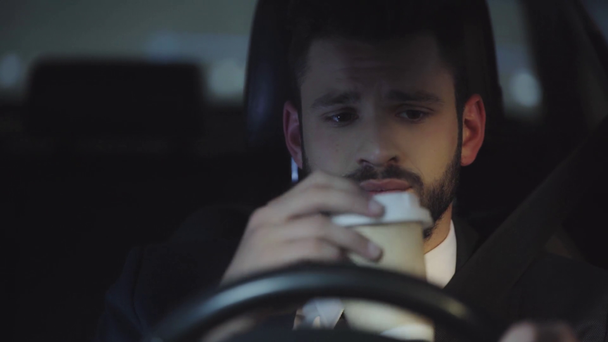 επιλεκτική εστίαση του όμορφου μουσάτο άντρα οδήγηση αυτοκίνητο και πίνοντας καφέ για να πάει  - Πλάνα, βίντεο