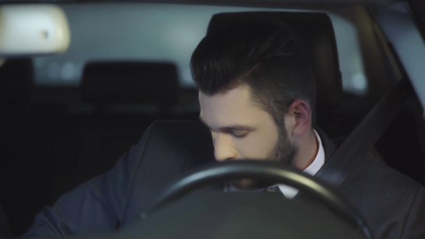 стійка фокус красивого чоловіка посміхається під час кріплення ременя безпеки і сидить в машині
  - Кадри, відео